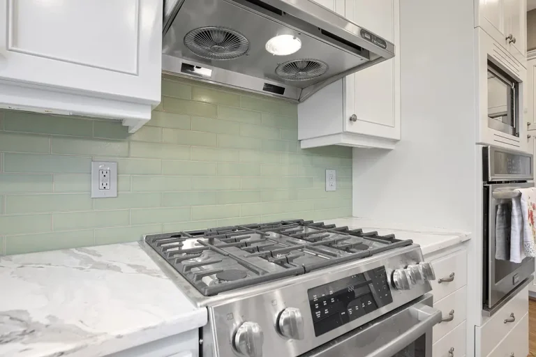 close-up-of-silver-metallic-stovetop-green-tile-wall-and-white-cabinets-for-kitchen-remodel-by-pdx-remodeling-and-design