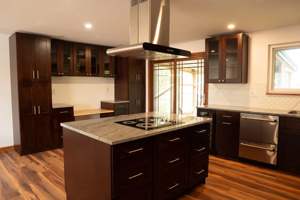 Modern kitchen remodel featuring dark espresso wood cabinets, a large island with stone countertops, and hardwood floors.